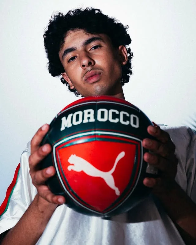 Close portrait of a young supporter holding a Morocco football toward the camera